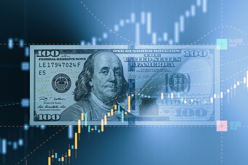 One hundred American Dollar bill surrounded by bar graph. Selective focus. Horizontal composition with copy space. Stock market and finance concept.
