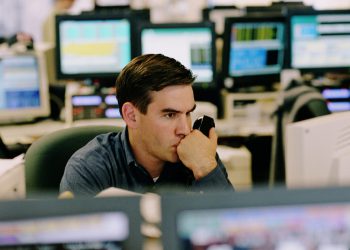 BROKER WATCHING STOCK AND HOLDING PHONE