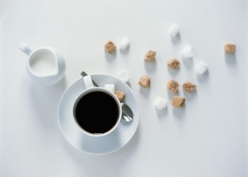 Cup of black coffee, milk in jar and sugar cubes, elevated view