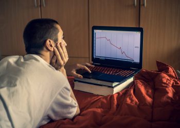 Young Adult Man Studying Market Crash in Bedroom