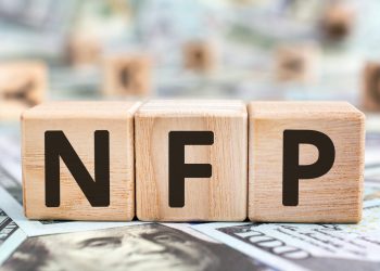 NFP - acronym from wooden blocks with letters, abbreviation NFP Nonfarm Payrolls key economic indicator or Natural Family Planning concept, random letters around, money background