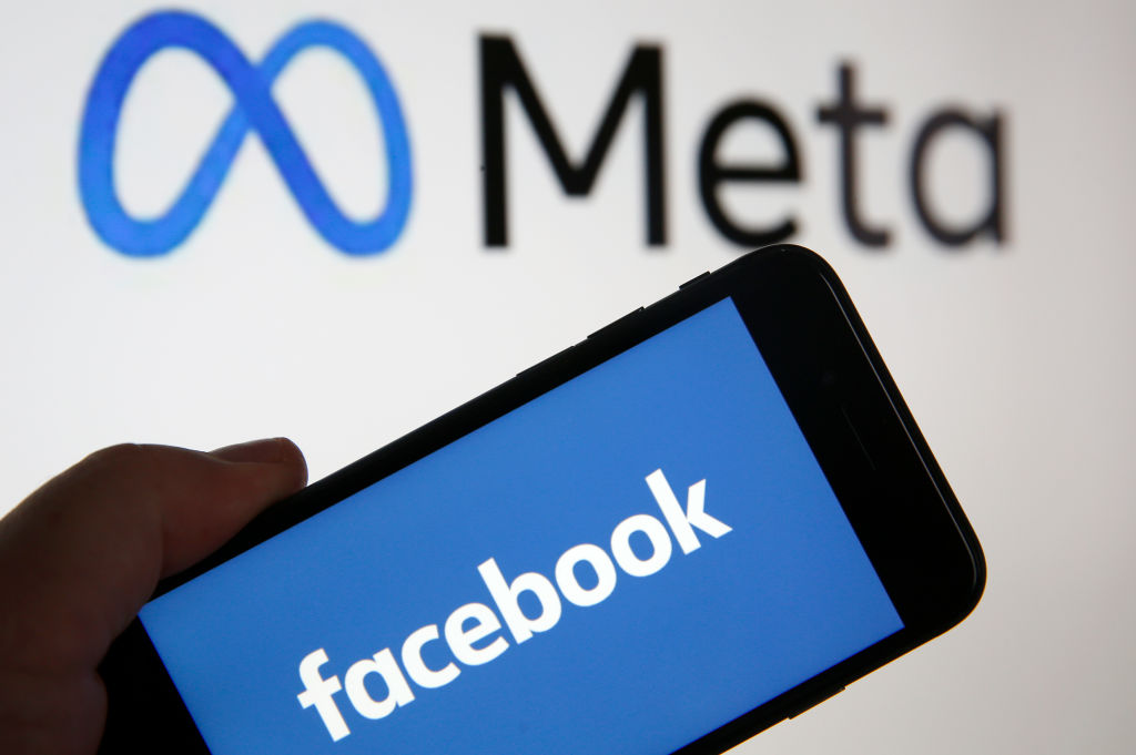 PARIS, FRANCE - OCTOBER 29: In this photo illustration, the Facebook logo is displayed on the screen of an iPhone in front of a Meta logo on October 29, 2021 in Paris, France. On October 28, during the Facebook Connect virtual conference, Mark Zuckerberg announced the name change of Facebook, believing that the term Facebook was too closely linked to that of the platform of the same name, launched in 2004. It is now official, the Facebook company changes its name and becomes Meta. (Photo illustration by Chesnot/Getty Images)