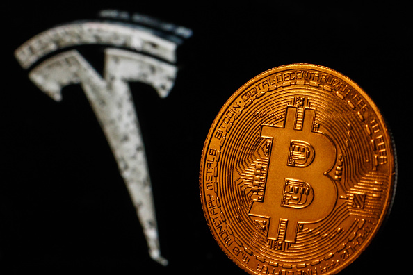 Representation of Bitcoin is seen with Tesla logo displayed in the background in this illustration photo taken in Krakow, Poland on July 9, 2021. (Photo by Jakub Porzycki/NurPhoto via Getty Images)