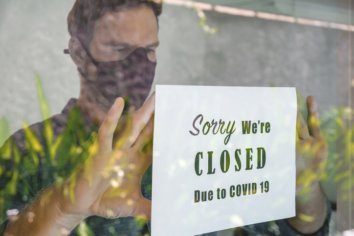 Portrait shot of business manputting a closing announcement message into the restaurant window due to Covid 19 pandemic