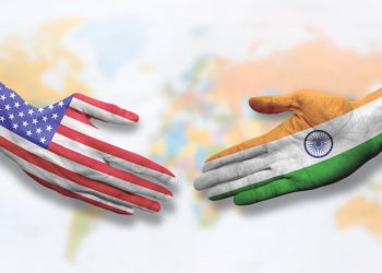 Hands colored like the flags of India and the United States symbolizing cooperation and friendship. Offering a handshake.