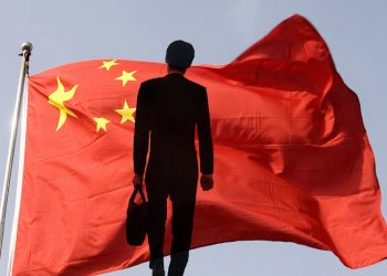 Businessman standing before Chinese flag.