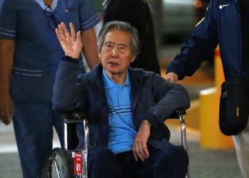 Peru's former President Alberto Fujimori waves to supporters as he is wheeled out of the Centenario Clinic in Lima on January 04, 2018, where he was hospitalised for the last twelve days and where he received a Christmas' eve pardon from President Kuczynski. - Fujimori was pardoned days after his son Kenji abstained from voting on Kuczynskis impeachment, drawing other lawmakers with him to deny the opposition the votes necessary to remove the president from office over corruption allegations. (Photo by LUKA GONZALES / AFP) (Photo by LUKA GONZALES/AFP via Getty Images)
