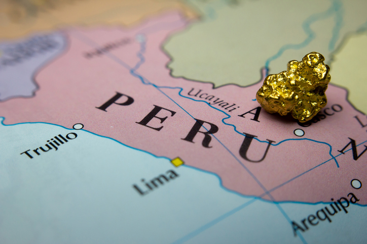 Close-up of a gold nugget and gold bar on top of an old map of Peru