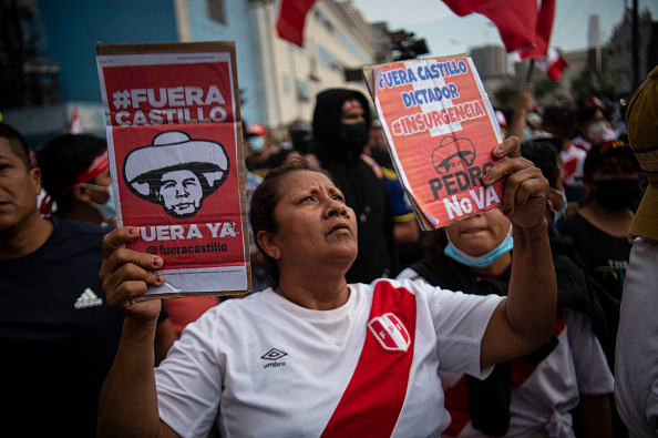 A woman holds signs during a protest against the governement of Peru's President Pedro Castillo, in Lima on April 05, 2022 - Peruvian President Pedro Castillo announced the end of a curfew in the capital Lima aimed at containing protests against rising fuel prices following crisis talks with Congress. (Photo by ERNESTO BENAVIDES / AFP) (Photo by ERNESTO BENAVIDES/AFP via Getty Images)