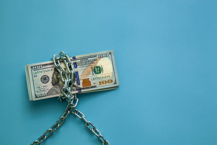 Hundred dollar bills wrapped in a chain on a blue background. Concept of economy, finance and exchange rate