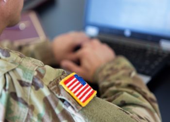 unrecognizable American soldier writing on a laptop