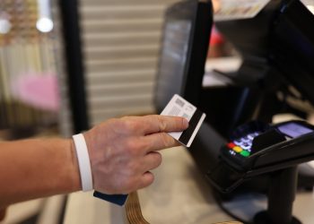 Man's hand holds a plastic card in his hands and applies it to terminal. Safe payments by bank cards concept