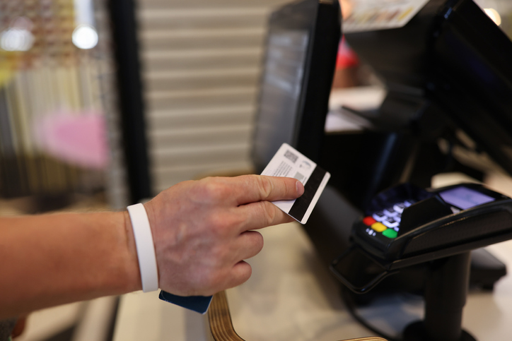 Man's hand holds a plastic card in his hands and applies it to terminal. Safe payments by bank cards concept
