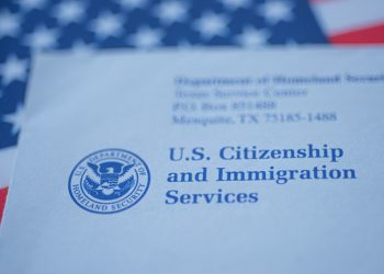 Hand touching Letter (Envelope) from USCIS on  flag of USA background. Close up view.