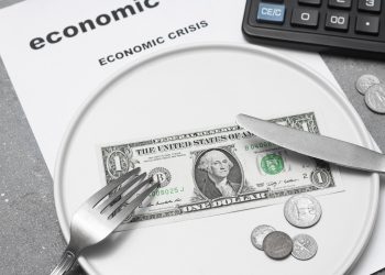 Economic crisis. One paper dollar with a fork and knife on a white plate Dividing the budget. Concept of the global financial crisis. Lack of money for food.
