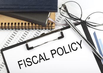 Text FISCAL POLICY on Office desk table with notebooks, supplies,analysis chart, on the white background.