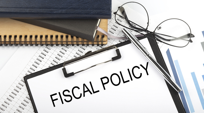 Text FISCAL POLICY on Office desk table with notebooks, supplies,analysis chart, on the white background.