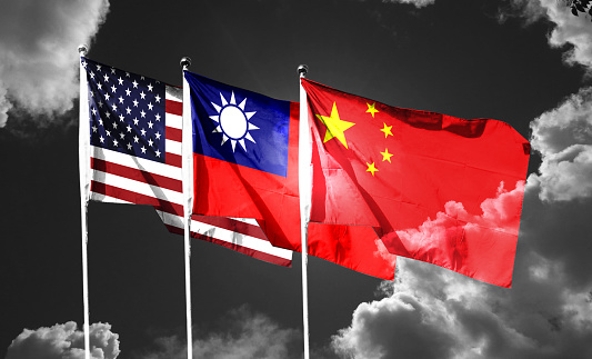 USA and China and Taiwan flags waving in the sky with dark clouds