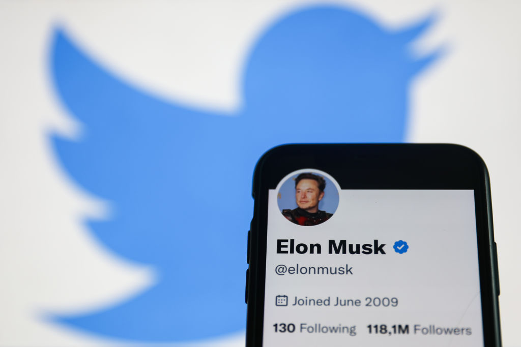Elon Musk Twitter account displayed on a phone screen and Twitter logo displayed on a screen in the background are seen in this illustration photo taken in Krakow, Poland on November 22, 2022. (Photo by Jakub Porzycki/NurPhoto via Getty Images)