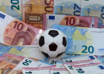 Symbol image: sport and money, football against a background of banknotes