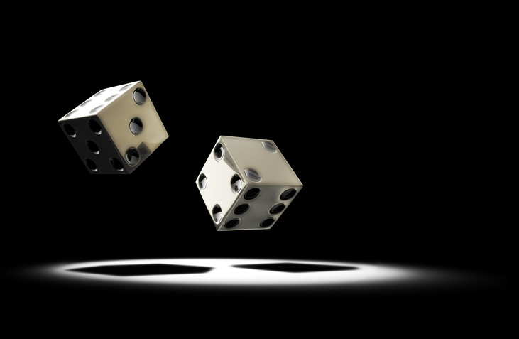 Two dice about to hit the ground. Dramatic spot lighting.