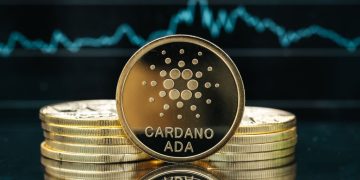 Physical Cardano cryptocurrency coin close-up, in front of a price chart
