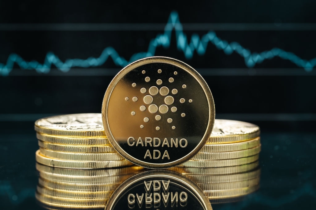 Physical Cardano cryptocurrency coin close-up, in front of a price chart