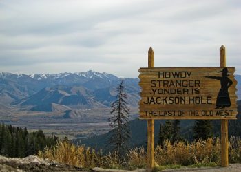 The sign reads "howdy stranger yonder is Jackson Hole, last of the old west. On top of Teton Pass Wyoming